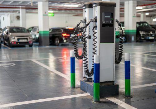 Electric vehicle charging stations with cables in underground parking area with cars