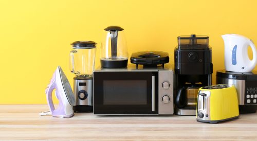 Different household appliances on table against yellow background