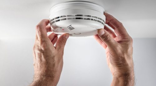Home smoke and fire alarm detector man installing, maintenance, checking, testing or replacing battery