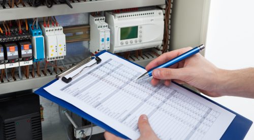 Cropped image of male electrician holding clipboard while examining fusebox